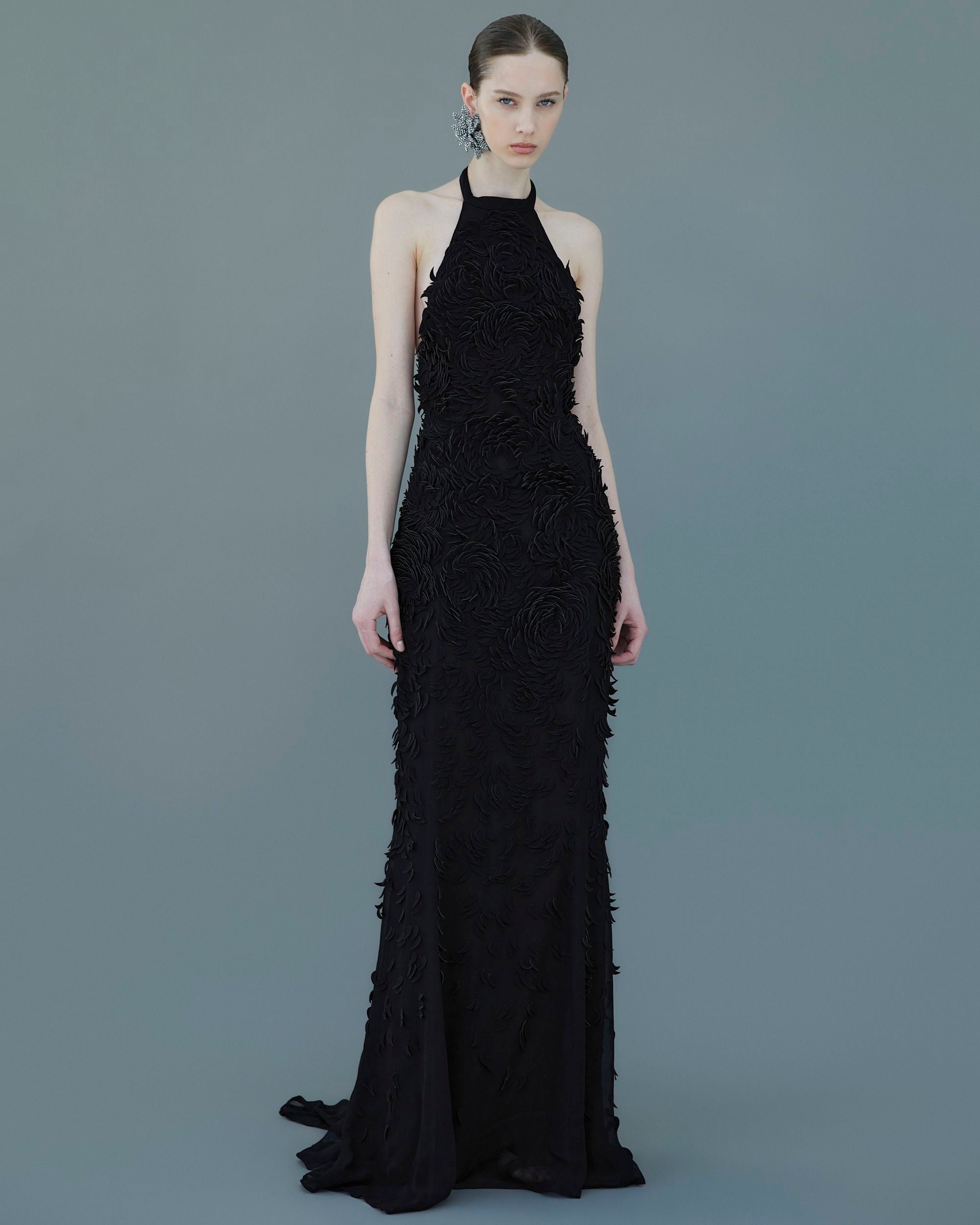 Model wearing AMEN black georgette gown with petal embroidery and flowing hem.