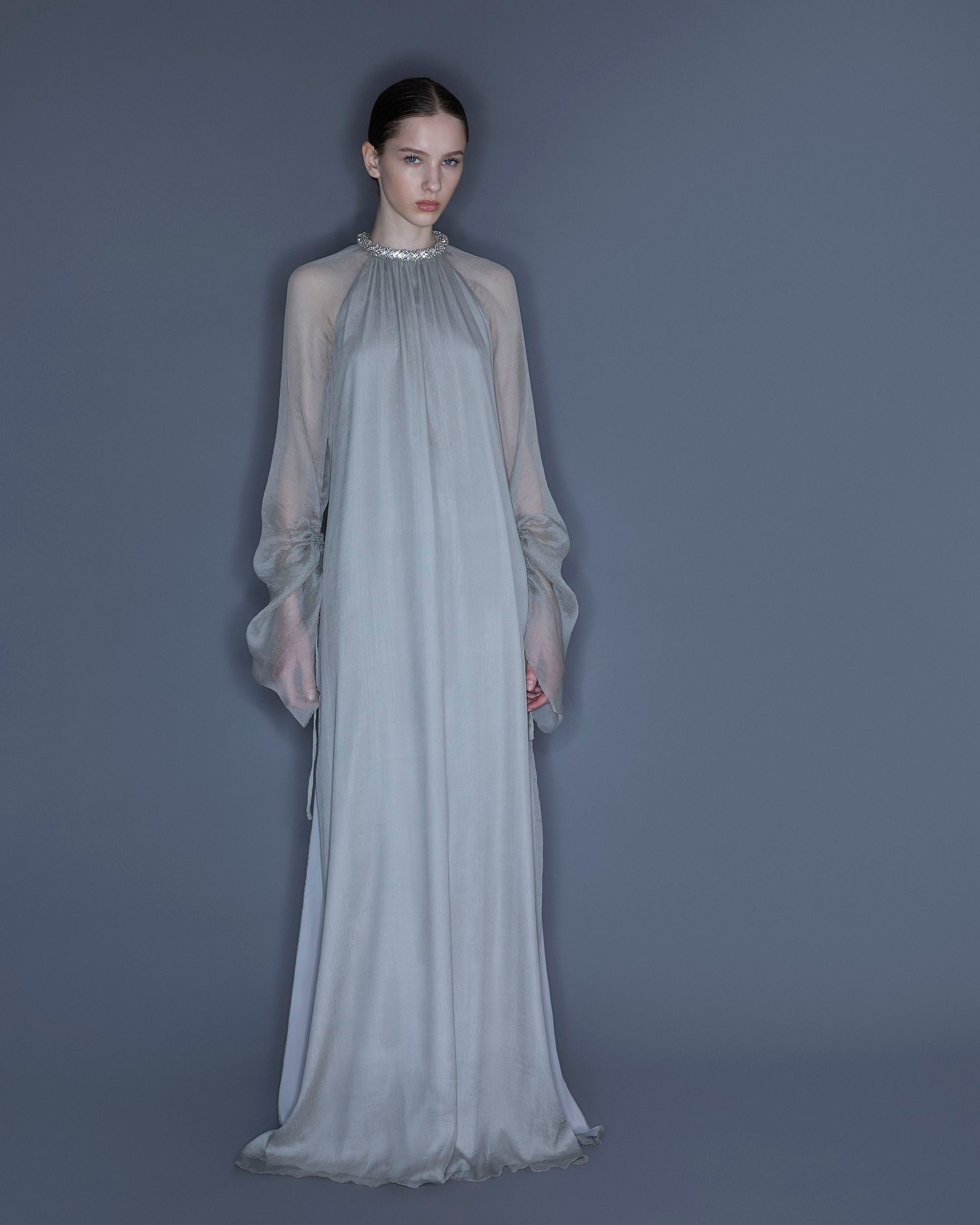 Model wearing silk chiffon long dress with torchón crystal neckline and flowing silhouette.