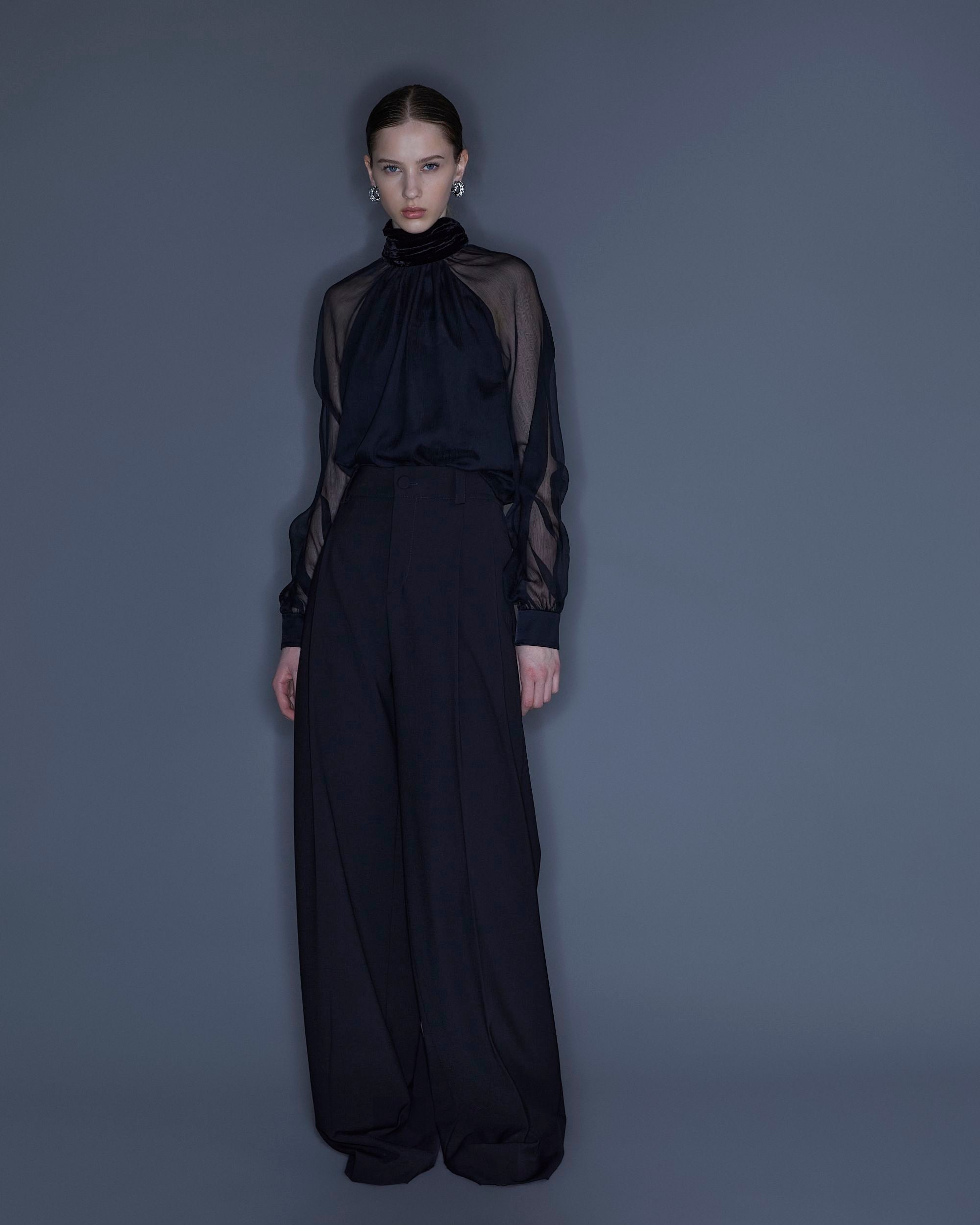 Black wool gabardine wide-leg pants with pleats and button closure.